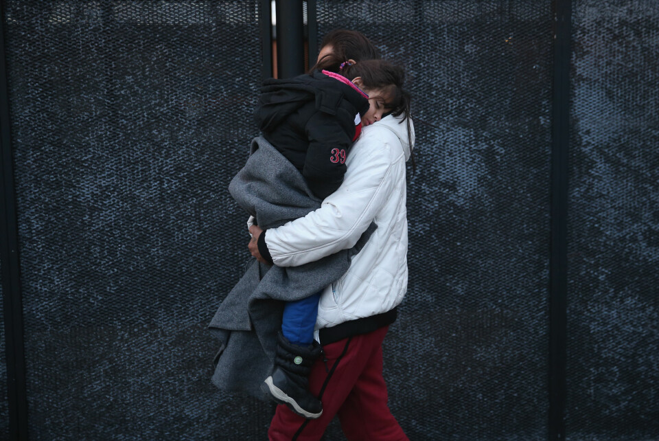 Stopp: En syrisk mann bærer sin datter til en politibil, etter at politiet i den danske byen Padborg sjekket identitetspapirene til passasjerene ombord et tog fra Tyskland, 6. januar. Foto: Sean Gallup/Getty images