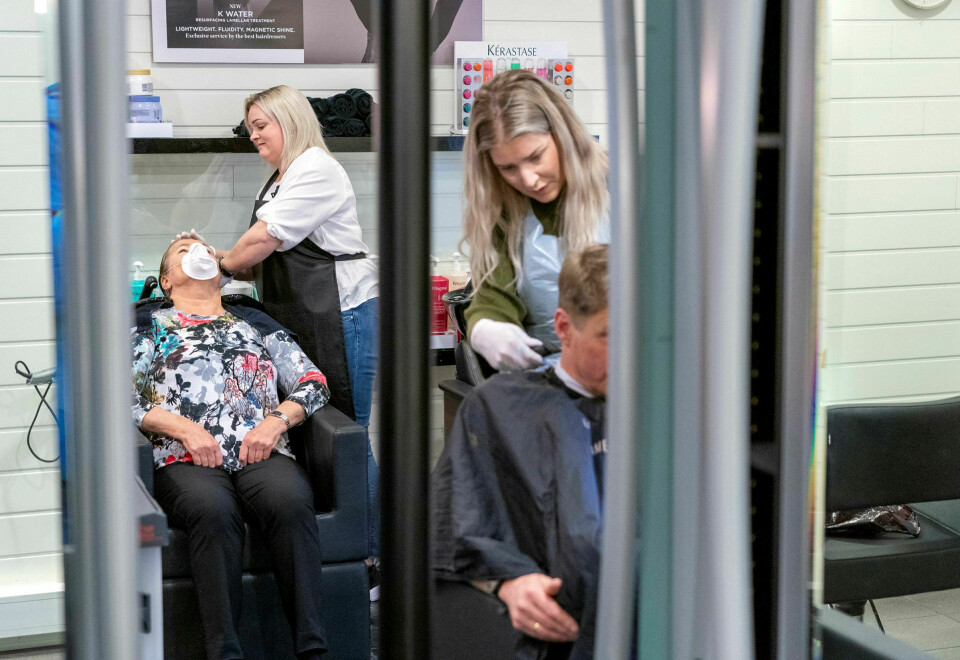 Trondheim 27. april: Unn Madsen (til venstre, med maske) var første kunde for Siv Andersson da Lade dame og herrefrisør åpnet mandag klokken 10. I forgrunnen klipper Charlotte Roaldseth en kunde. Foto: Gorm Kallestad / NTB scanpix