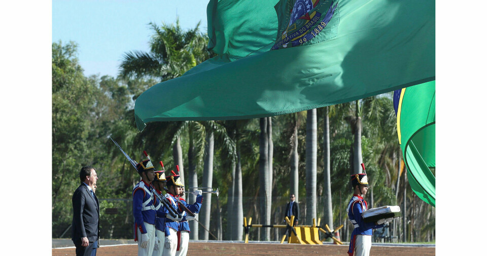 Kampanje: Brasils president oppfordrer til feiring av kuppet i 1964. Her foran flagget i hovedstaden Brasilia. Foto: Handout / Reuters / NTB scanpix