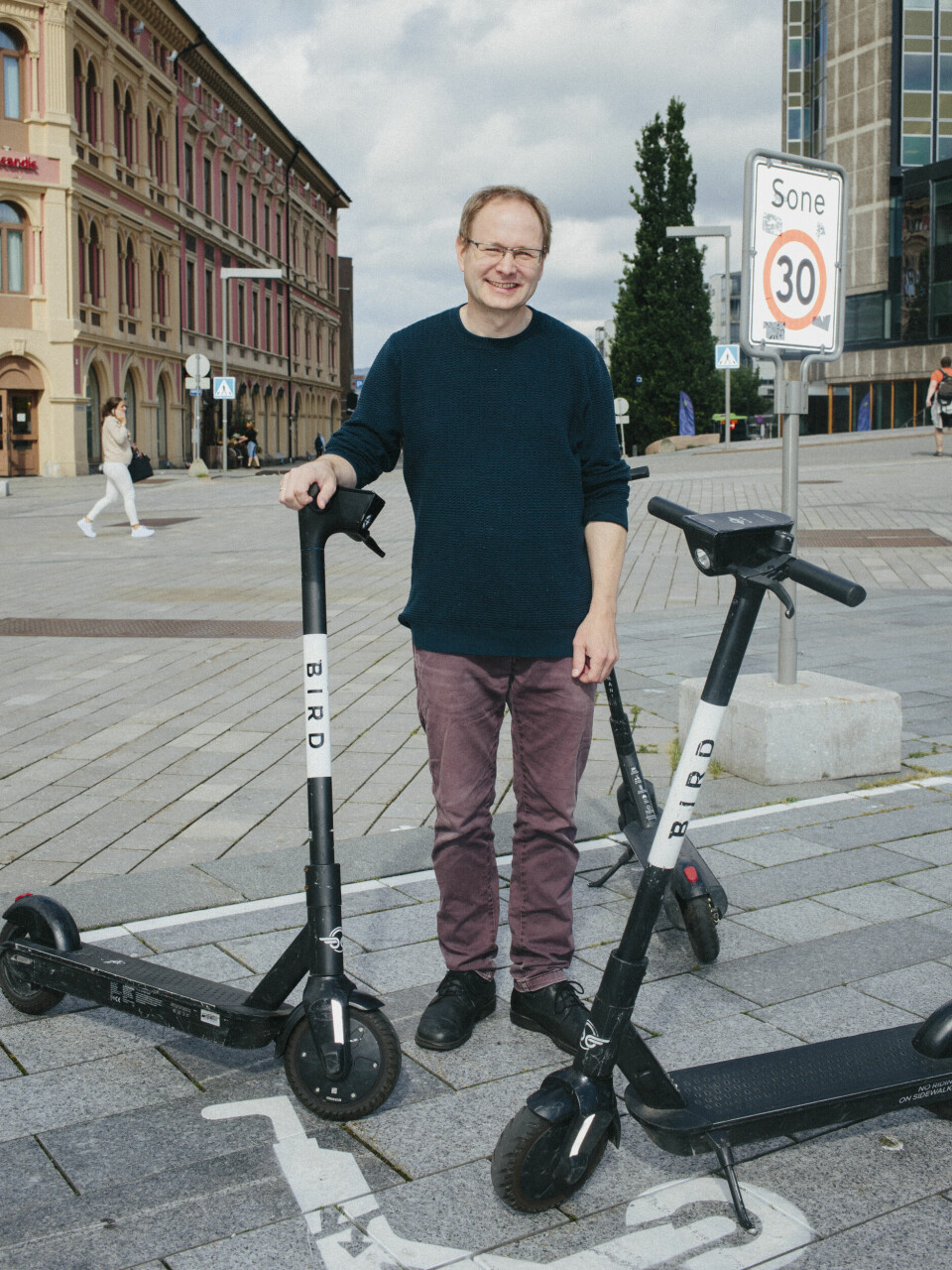 Mobilt hodebry: Et uregulert marked har skapt et elsparkesykkel-race mot bunnen, mener forsker Nils Fearnley. Her står han omringet av stridens kjerne i Drammen sentrum.